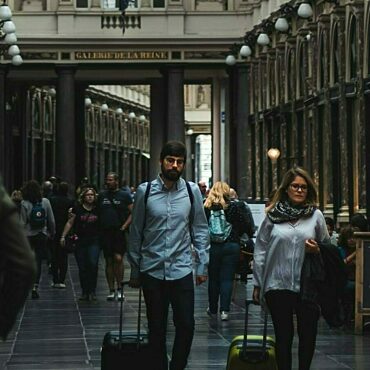 Two students with luggage in gallery in Brussels.